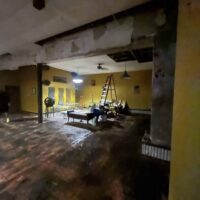 Modern event hall renovation with damaged interior, construction ladder, and setup in progress for special gatherings at Do it a-Ginn Event Hall.