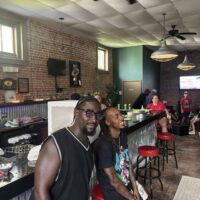 Hot and stylish young men enjoying a lively event at Do it a-Ginn Event Hall, featuring a vibrant atmosphere, exposed brick walls, and modern decor, perfect for celebrations and gatherings.