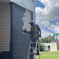 Painted exterior wall of Do it a-Ginn Event Hall with power spray gun, showcasing professional exterior painting services for event venues and commercial buildings.